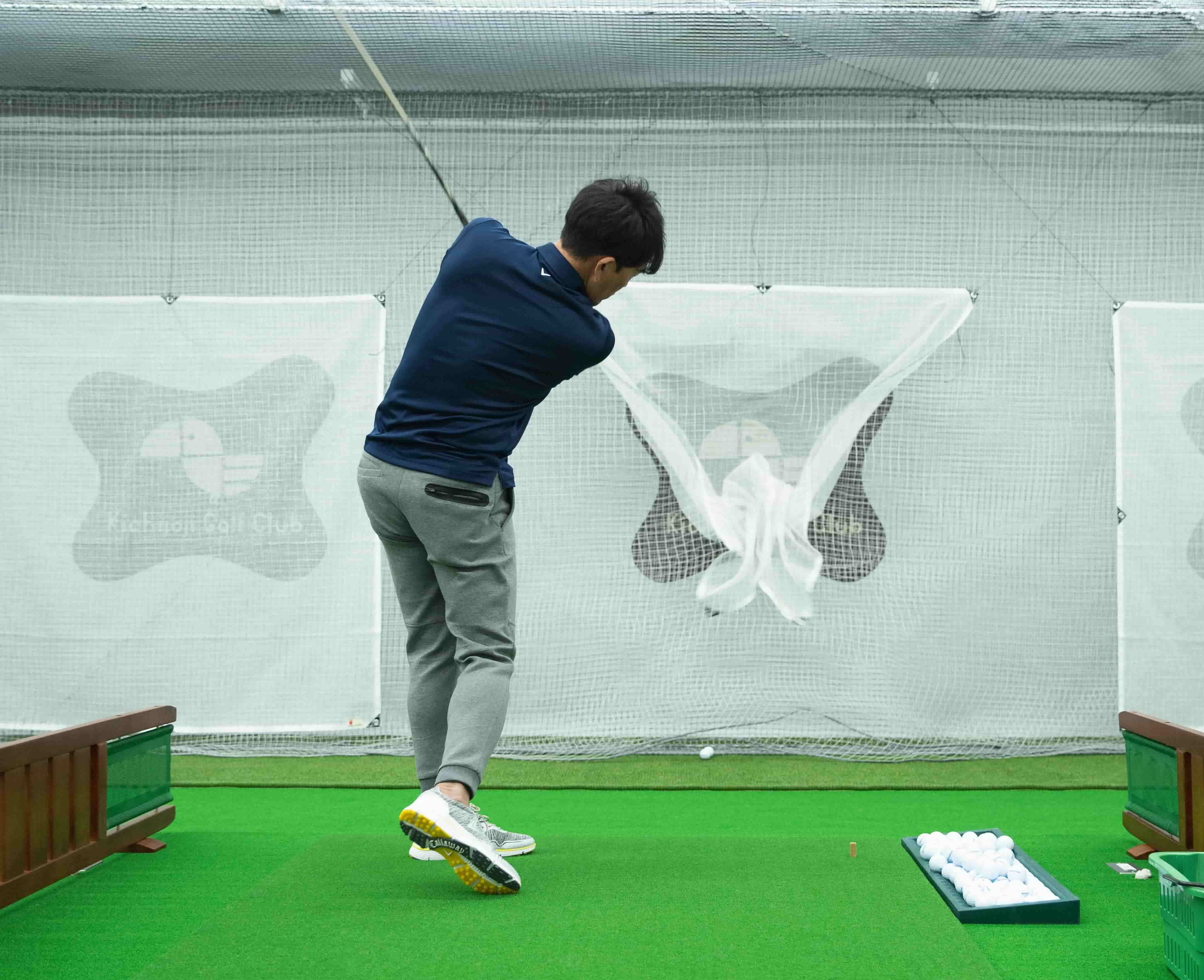 吉祥寺ゴルフ倶楽部のインドア打席でスイングを練習する様子